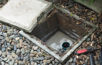 plumber repairing clogged grease trap with auger machine